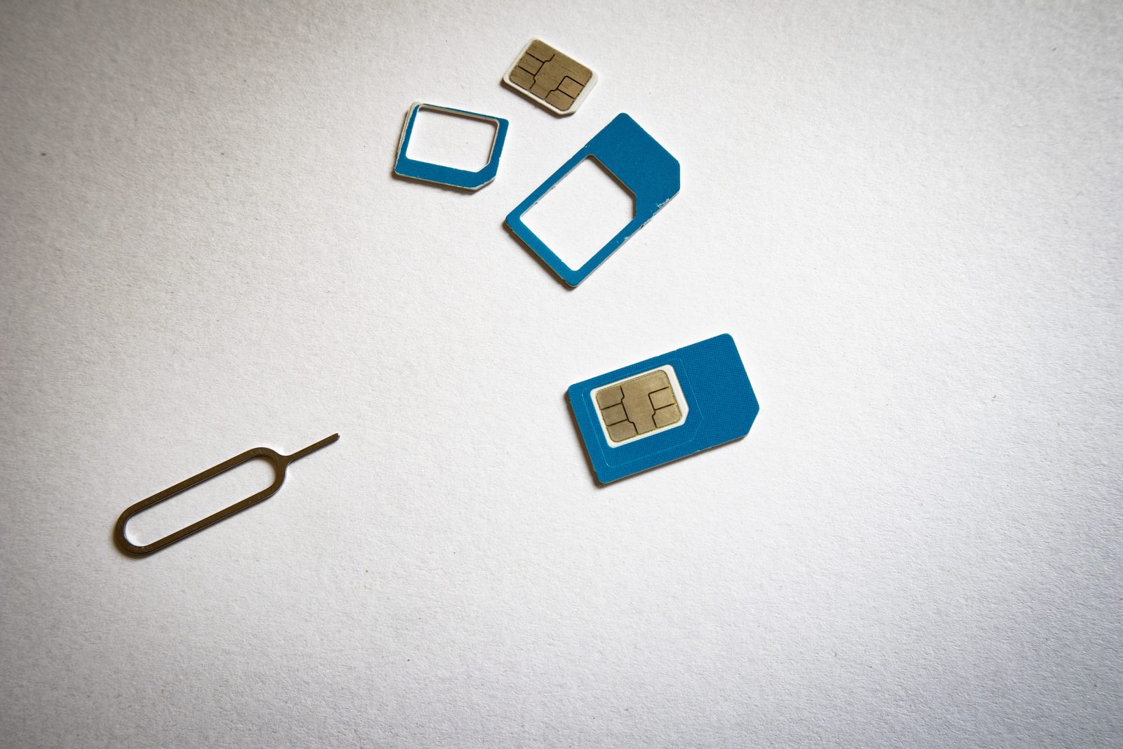 Blauwe simkaart in verschillende formaten met adapters en een simtool op een witte achtergrond