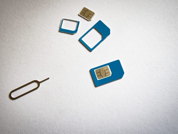 Blauwe simkaart in verschillende formaten met adapters en een simtool op een witte achtergrond