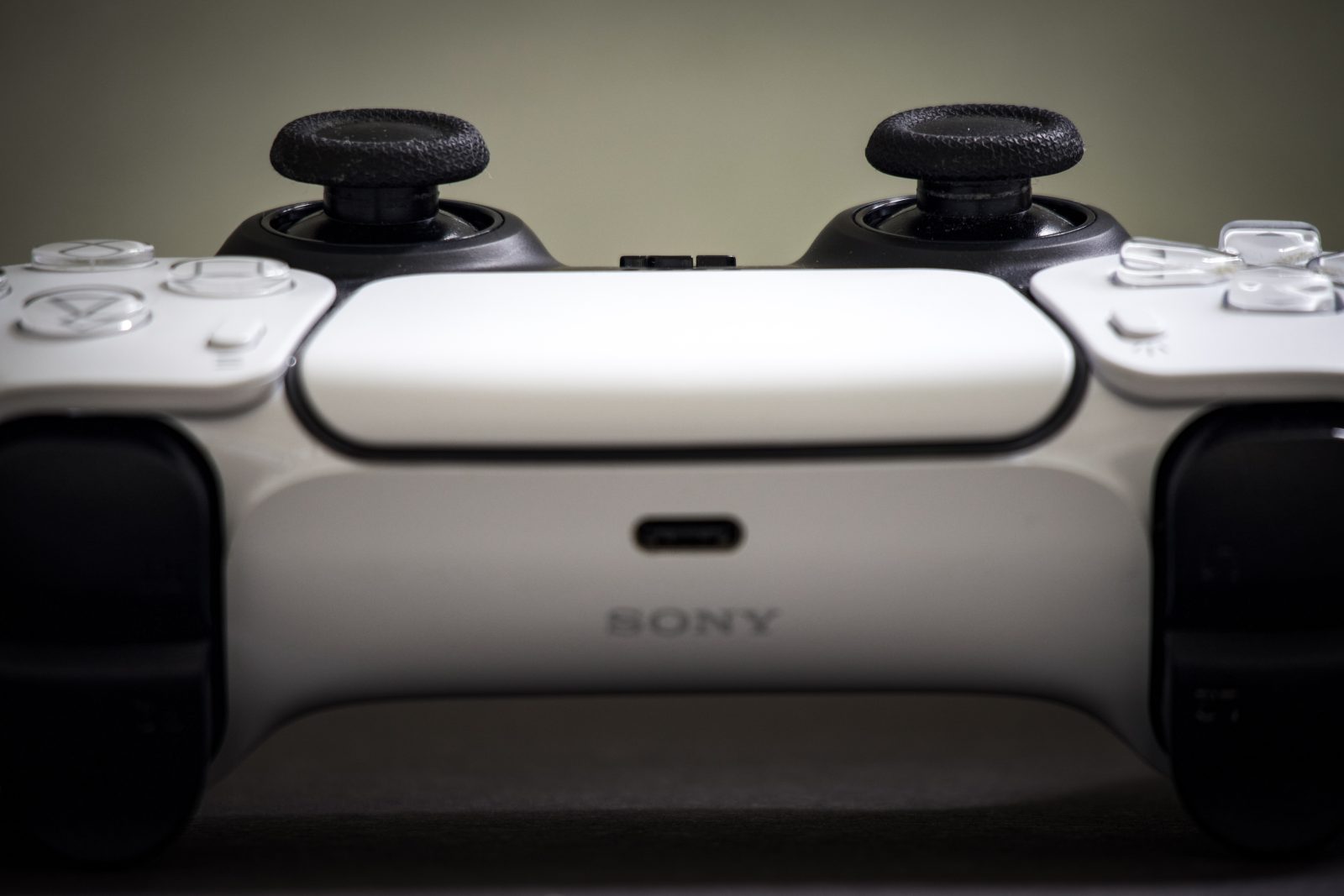 Frontale macro opname van een witte PlayStation DualSense controller, met de twee joysticks bovenaan en het Sony logo in het midden