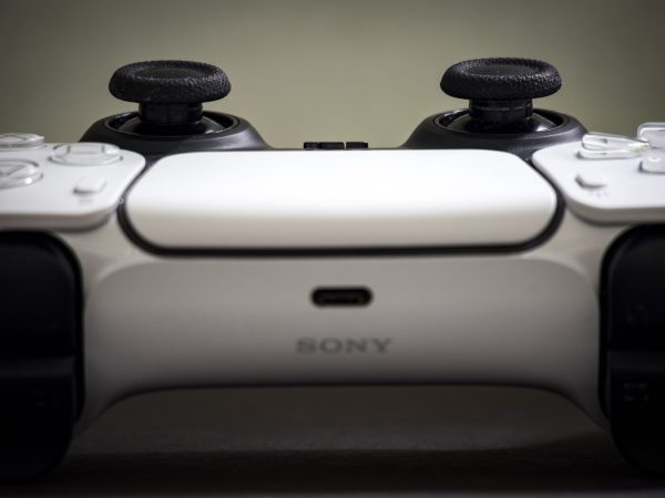 Frontale macro opname van een witte PlayStation DualSense controller, met de twee joysticks bovenaan en het Sony logo in het midden