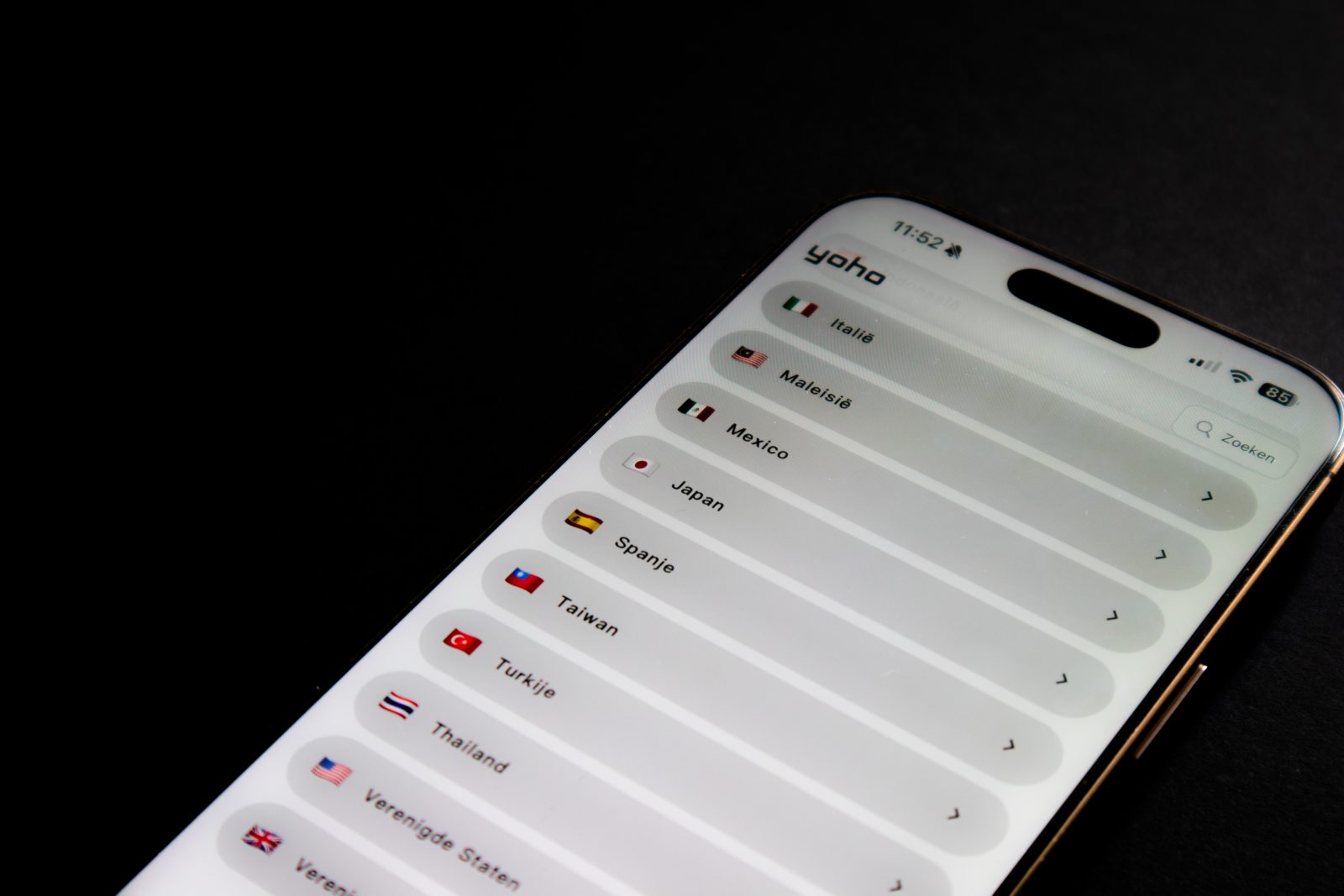 Smartphone with the Yoho eSIM app and a list of countries with flags against a black background