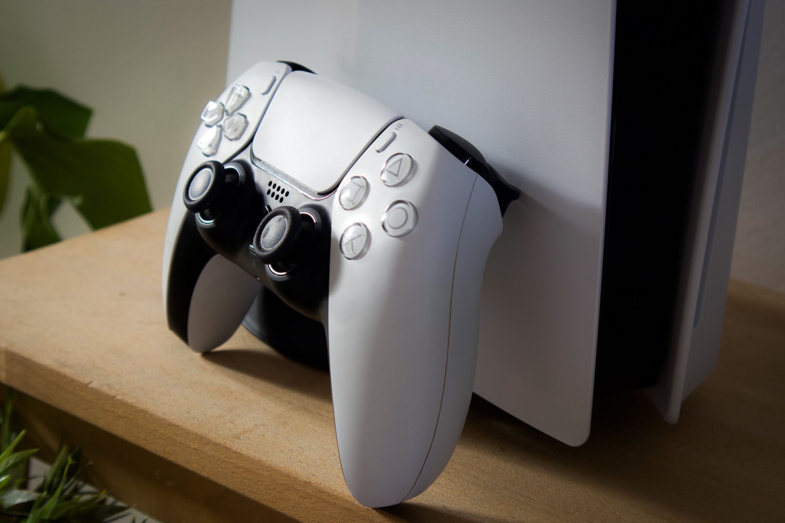 Sony PlayStation 5 controller leunend tegen de console op houten plank
