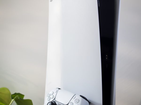 PlayStation 5 console rechtop op houten plank in woonkamer met een groene hint van een plant
