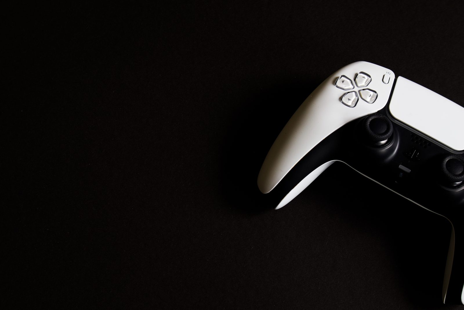 Witte PlayStation 5 DualSense controller in de rechterbovenhoek tegen een zwarte achtergrond