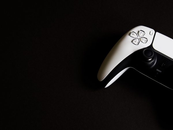 Witte PlayStation 5 DualSense controller in de rechterbovenhoek tegen een zwarte achtergrond